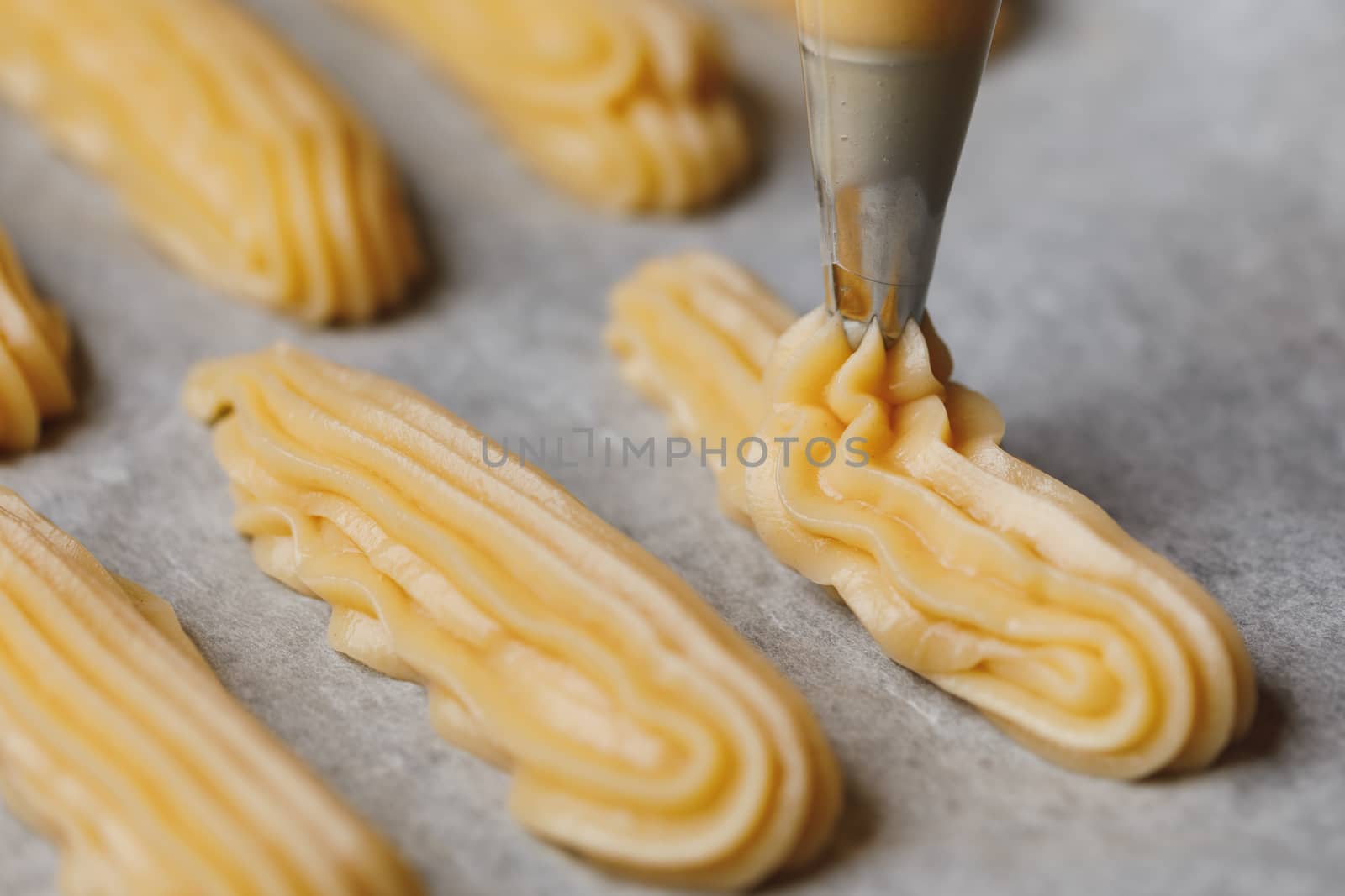 raw eclairs choux pastry on the baking tray by nikkytok