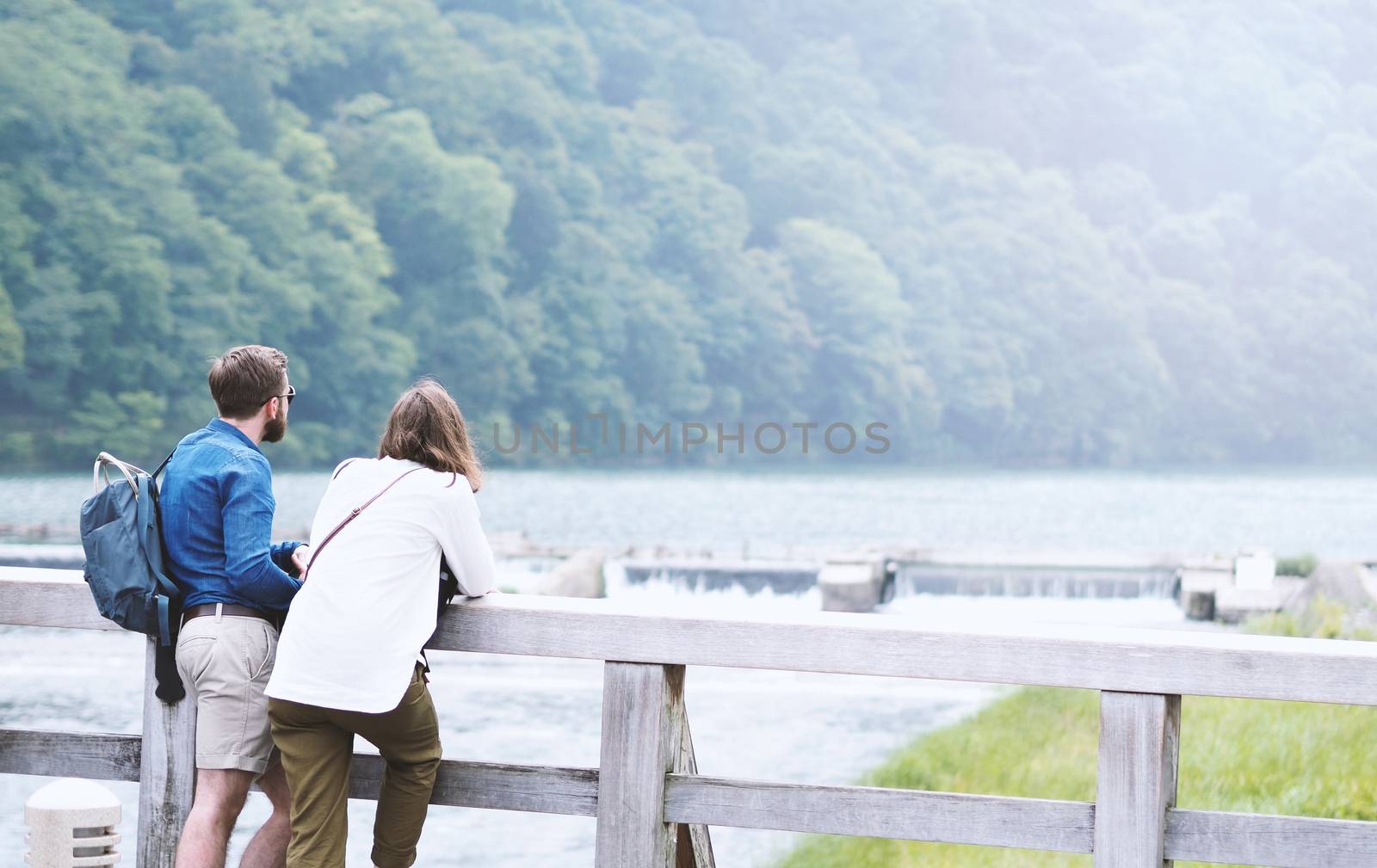 Couple casual traveller man and woman standing on a romantic old wood Arashiyama bridge in Kyoto Japan.