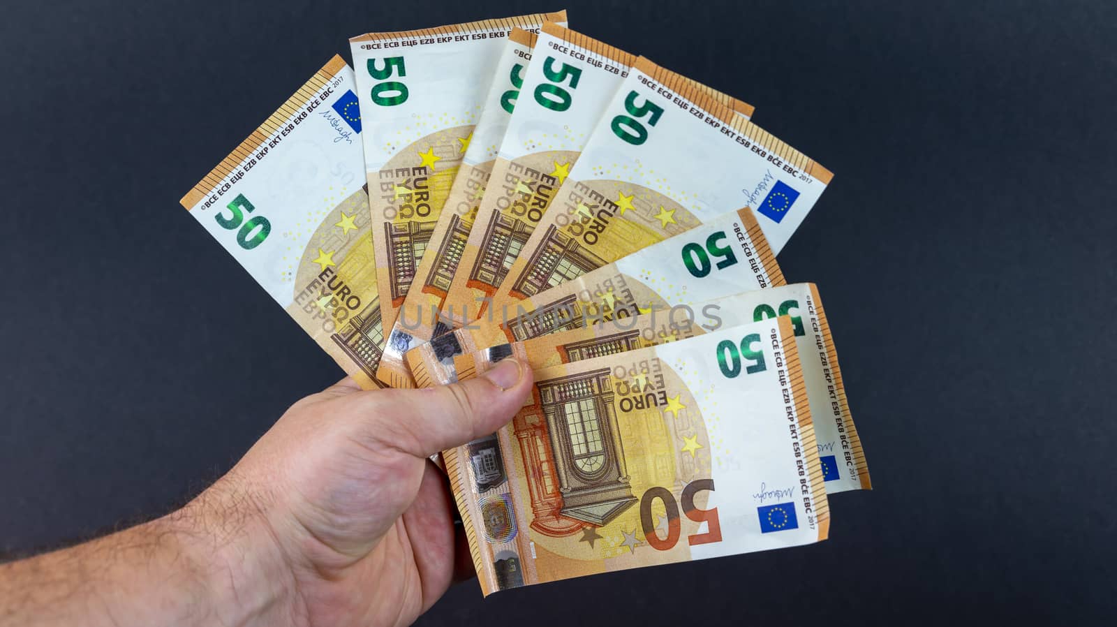 man with 50 euro bills holding them in a fan shape
