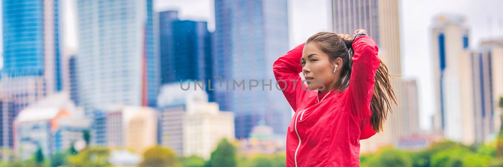 City running healthy lifestyle banner runner woman tying ponytail hair getting ready to run in urban background. Horizontal panorama crop. Asian sport girl by Maridav