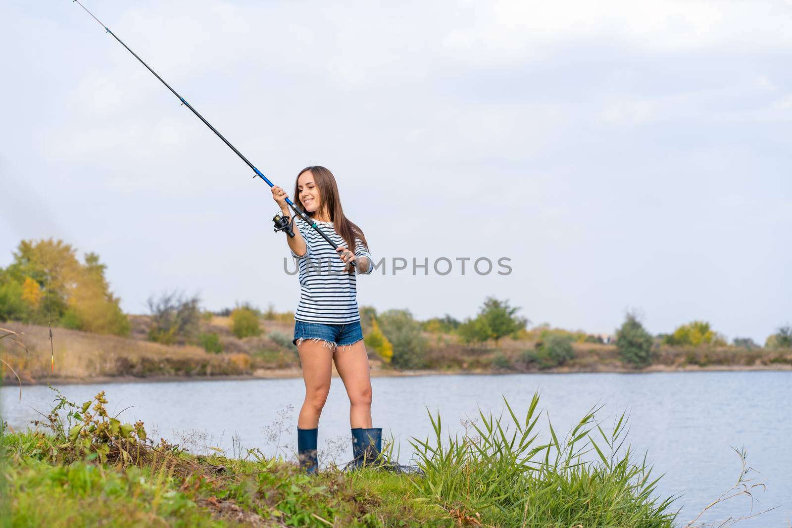 Beautiful young girl fishes on the lake