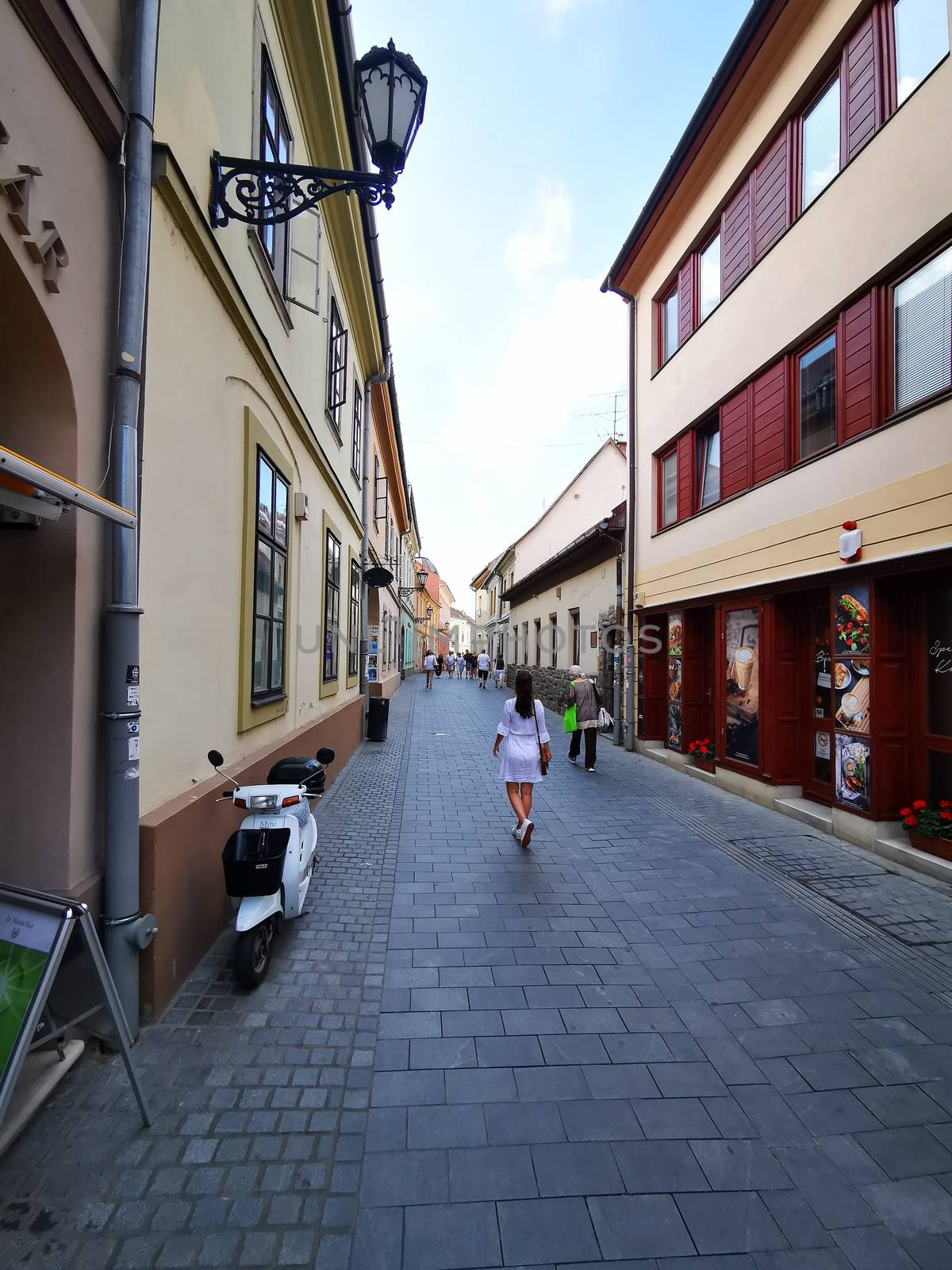 Pretty young girl walks in the beautiful, historic centre of Eger. High quality photo