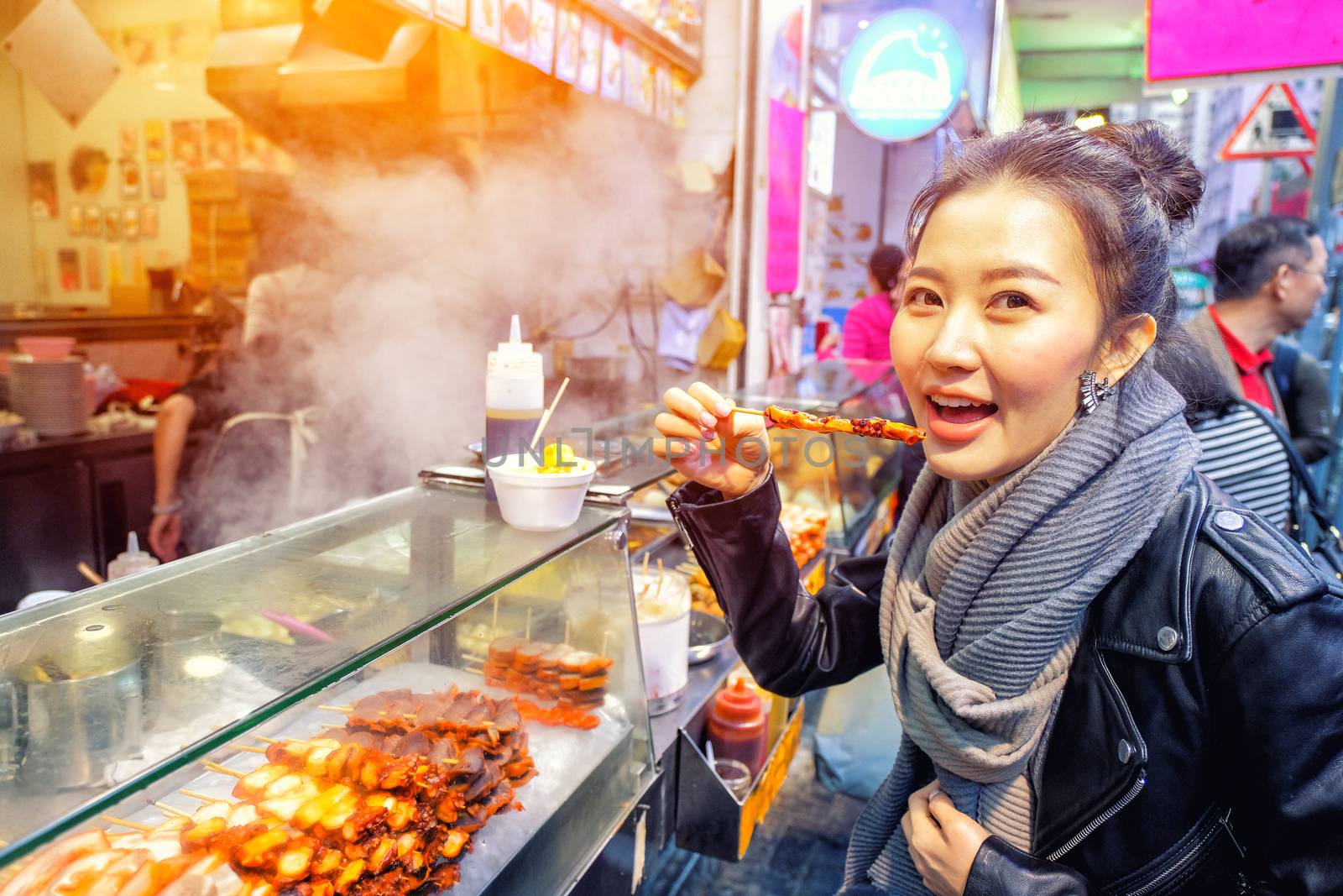 Chinese Asian young female model eating Grilled octopus on Street in Hong Kong