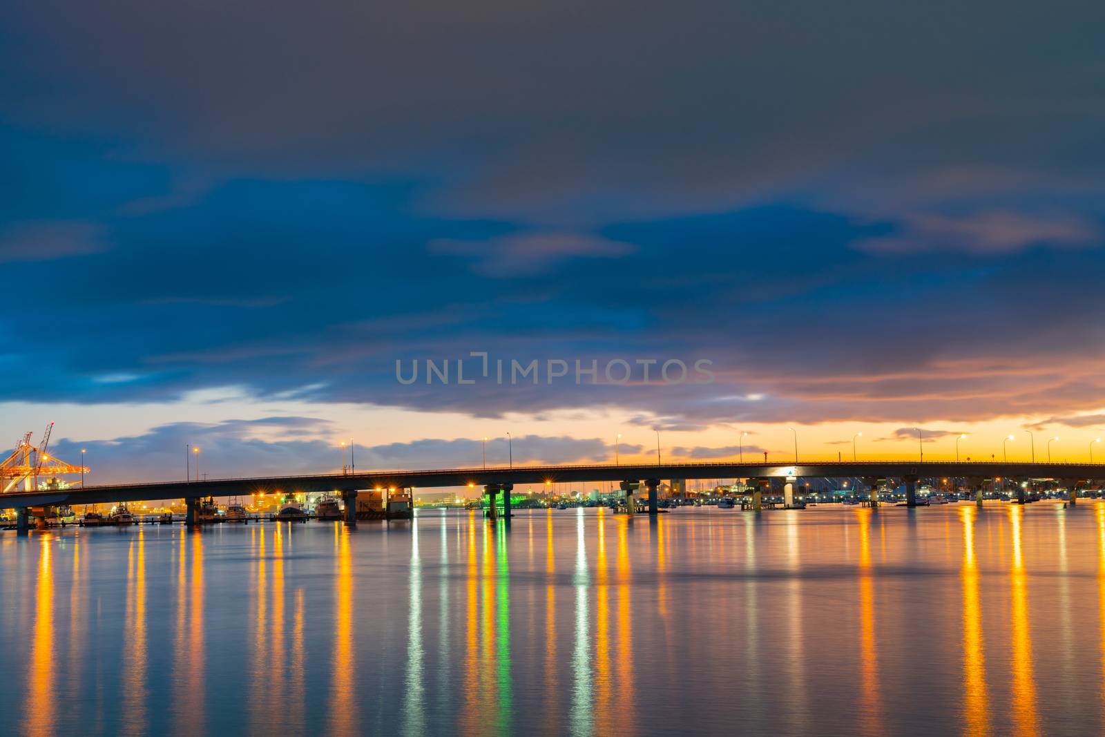 Tauranga  Harbour Bridge lights and reflections before sunrise under dark sky.