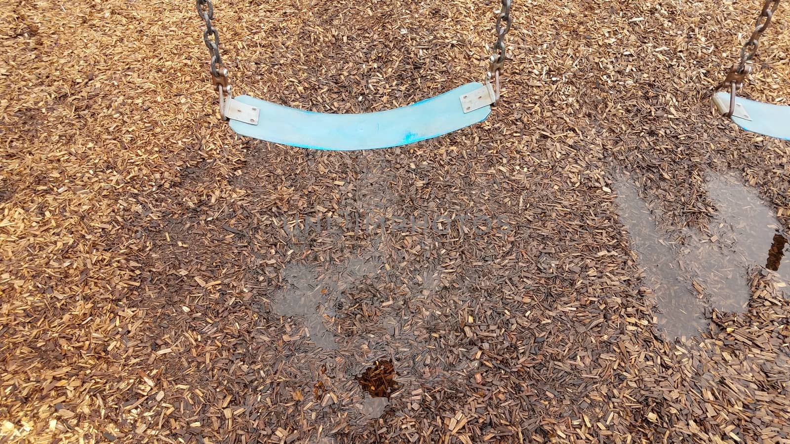 blue seat on swing with water puddle and mulch by stockphotofan1