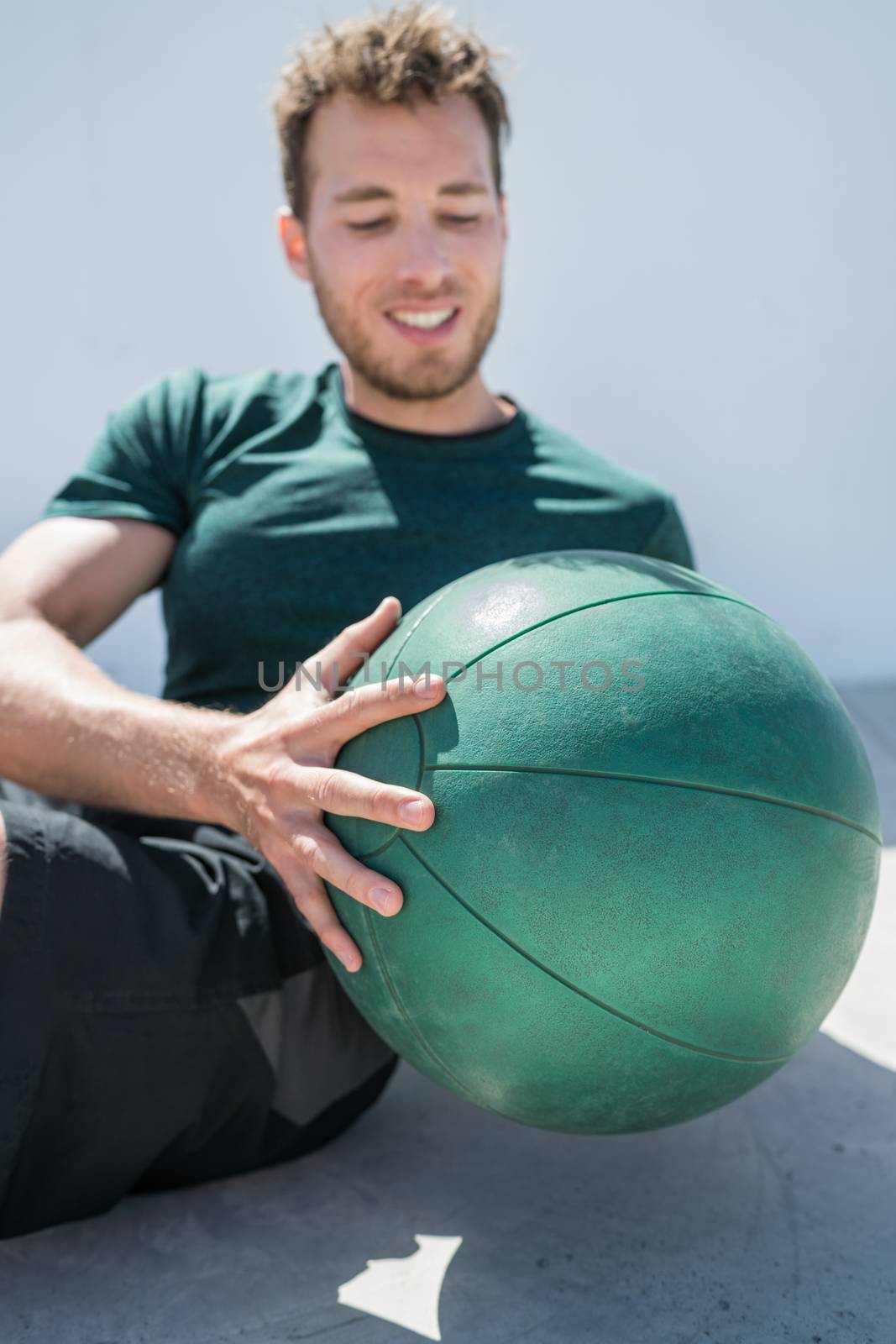 Medicine ball exercise russian twist for body fitness. Fit Man training abs workout using equipment at gym.