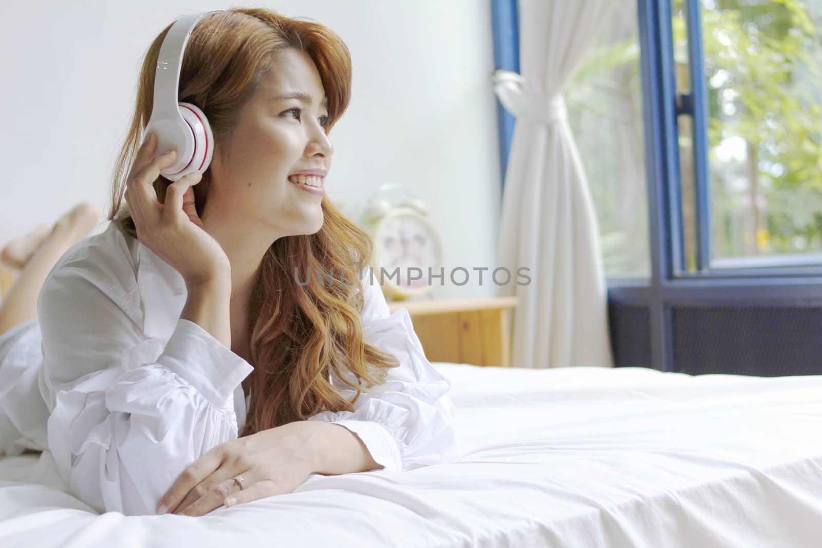 woman listening to music lying in bed by BirdKS