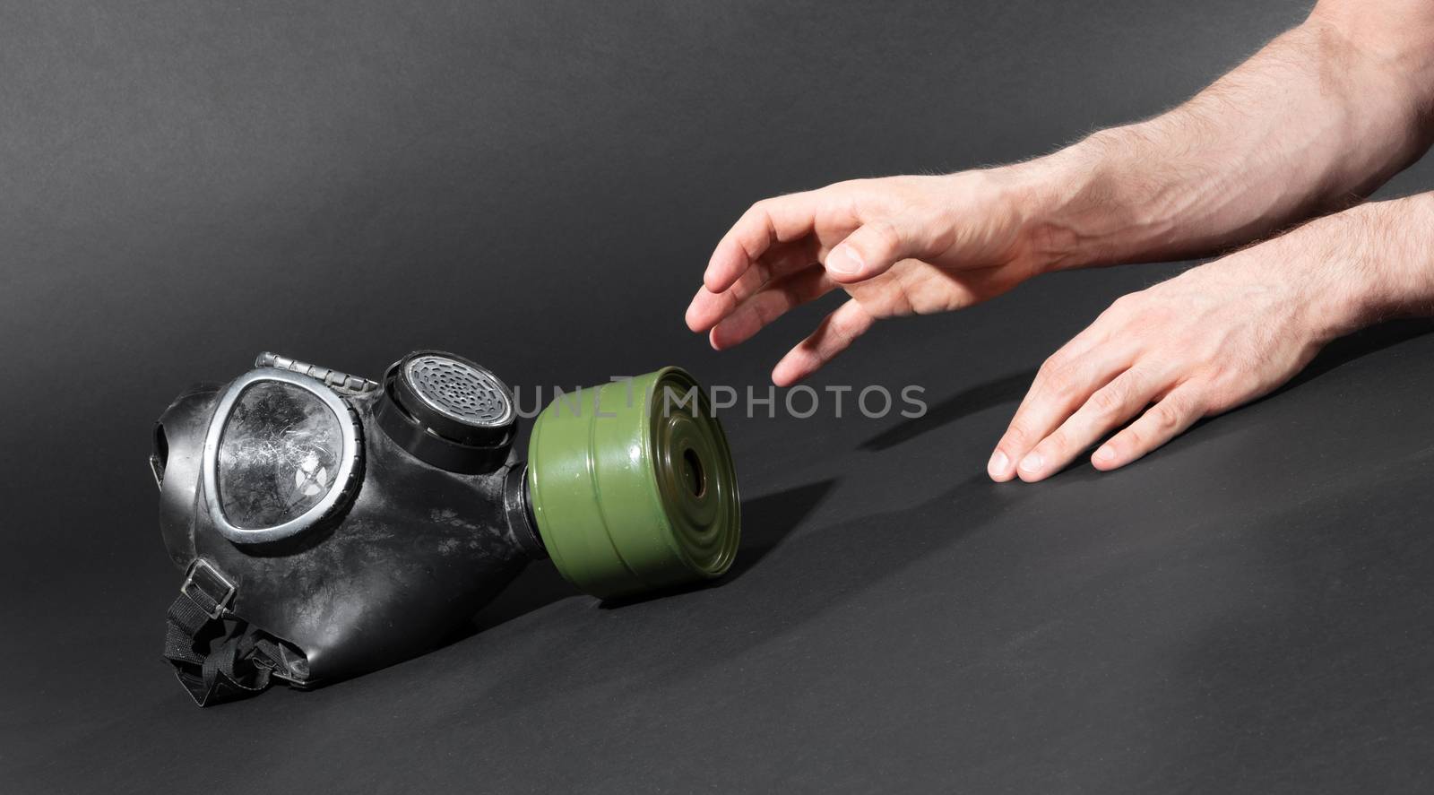 Man in room, trying to reach for vintage gasmask - Isolated on black - Green filter