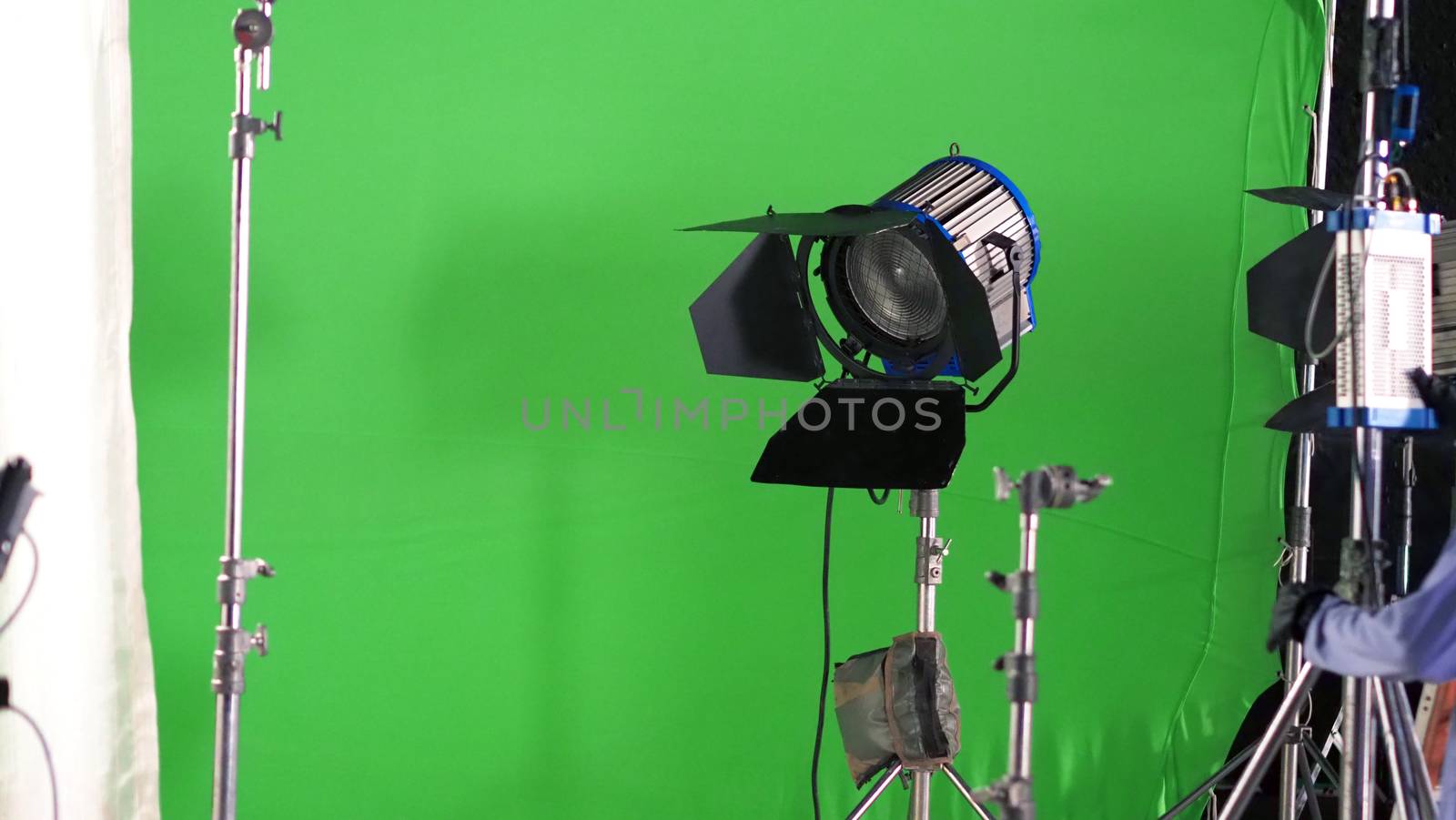 Big studio LED spotlight for video movie or photo film production with green screen background for chroma key technique in post lab process and professional equipment such as tripod and others.