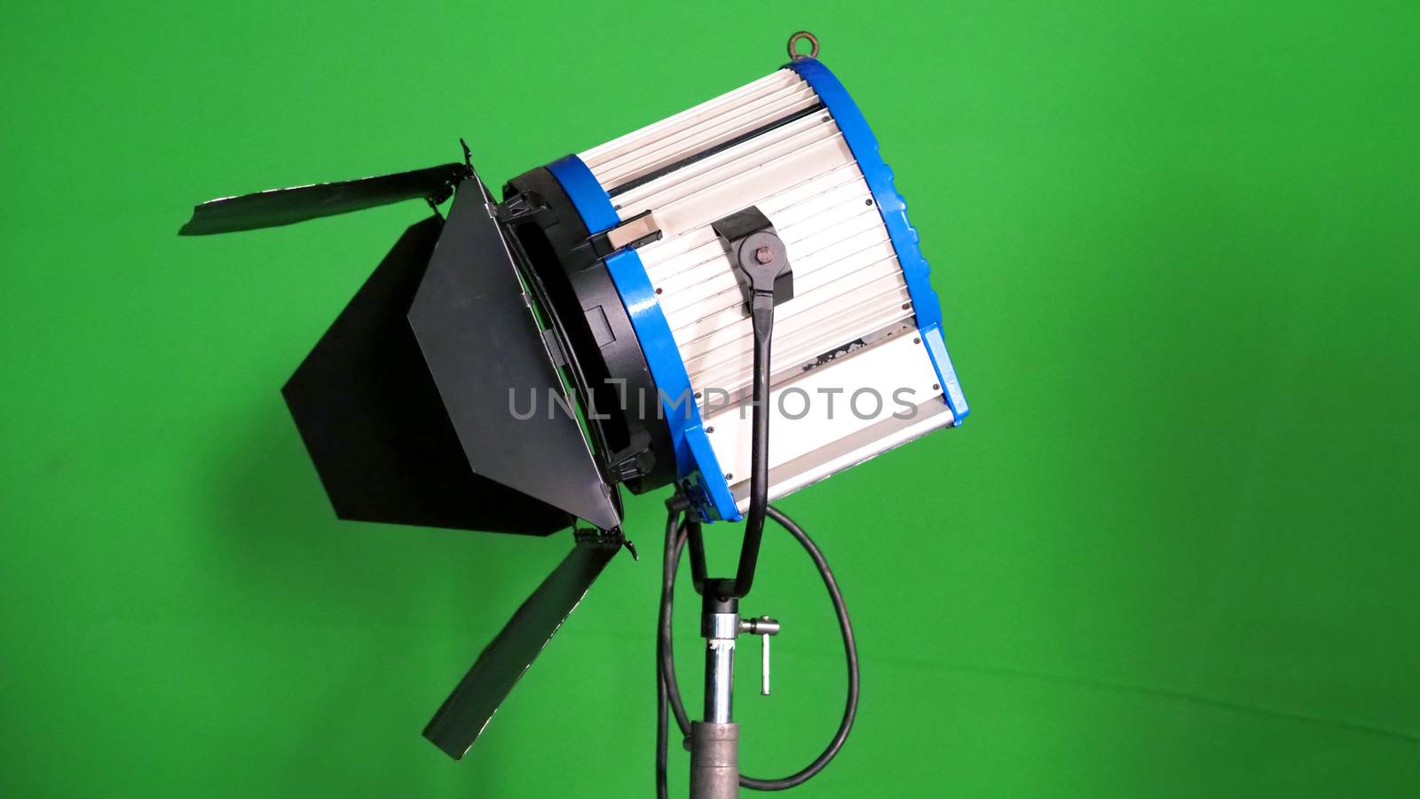 Big studio LED spotlight for video movie or photo film production with green screen background for chroma key technique in post lab process and professional equipment such as tripod and others.