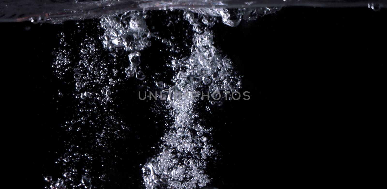 Blurry images of clear transperant soda liquid bubbles splashing or sparkling and moving up in black background for represent the refreshing moments after drink carbonated water.