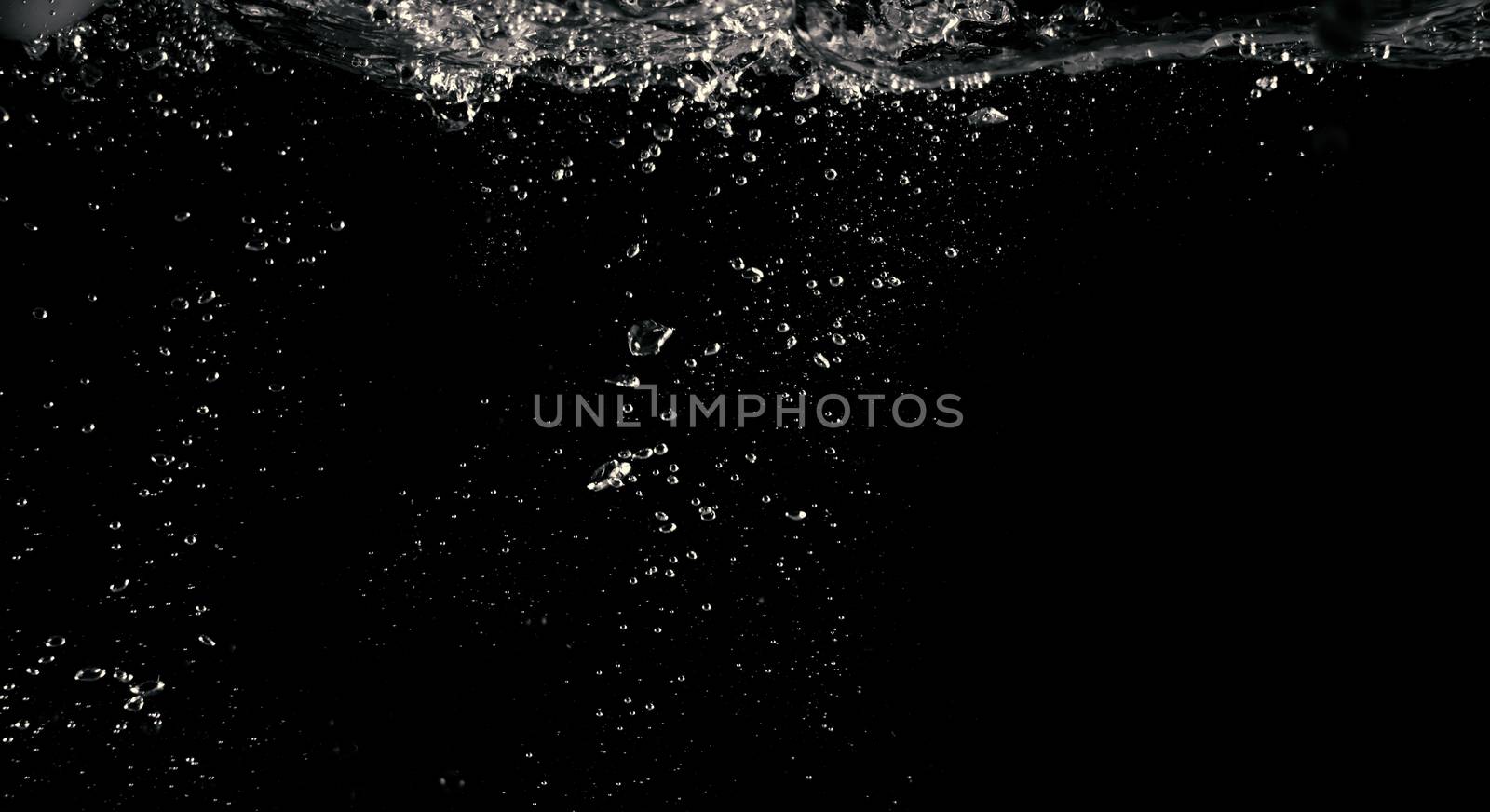 Blurry images of clear transperant soda liquid bubbles splashing or sparkling and moving up in black background for represent the refreshing moments after drink carbonated water.