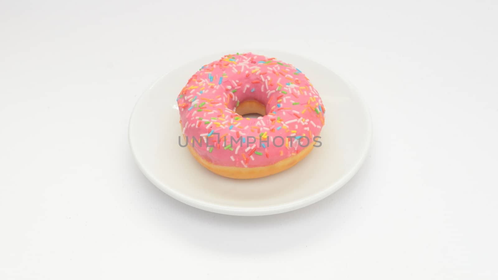 One pink glazed donut on plate on white background.Sweet dessert food for snack by andre_dechapelle