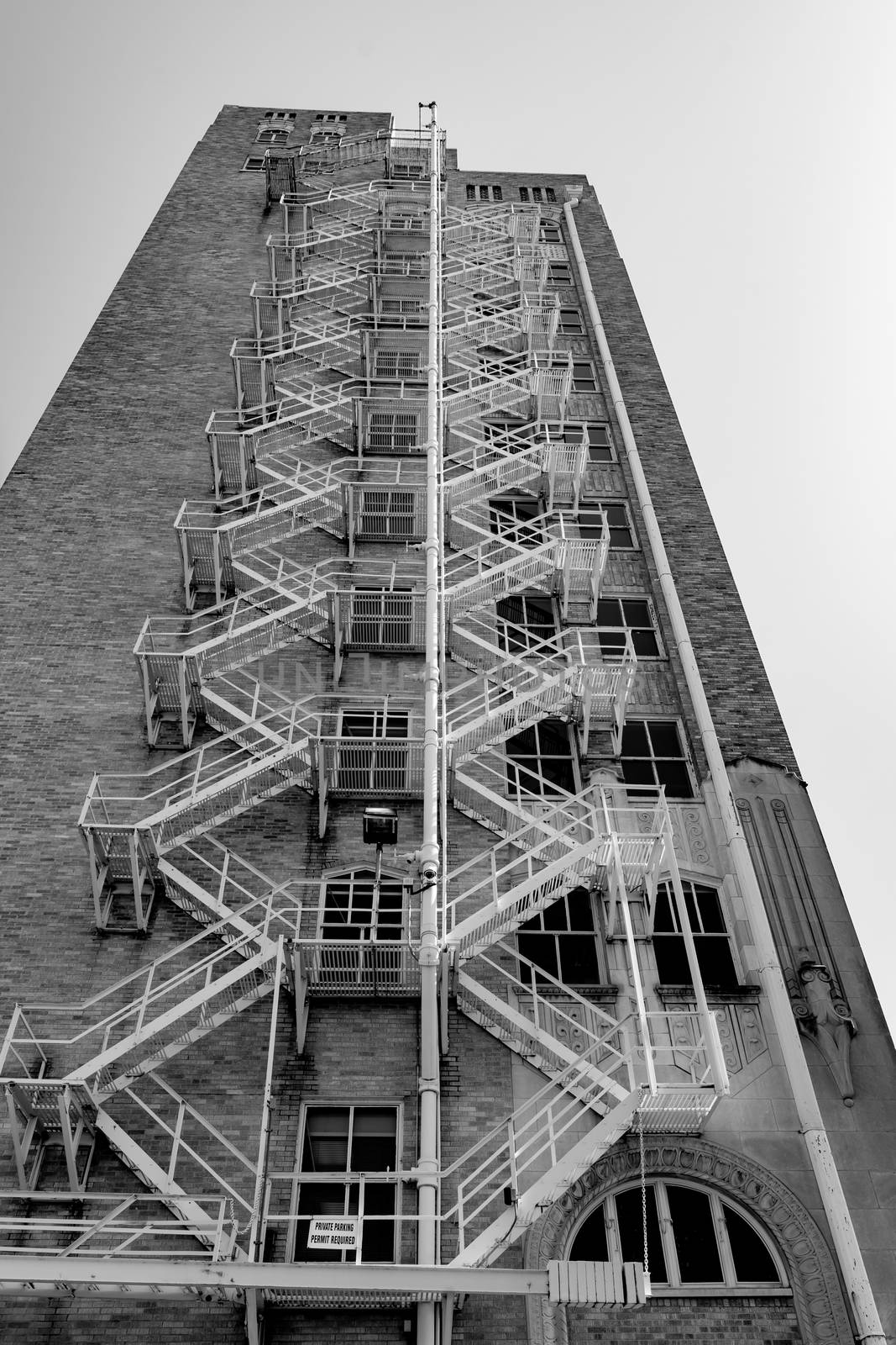 Old style exterior fire escape stairs on buidling in Tulsa, Oklahoma USA vertical composition in monochrome.