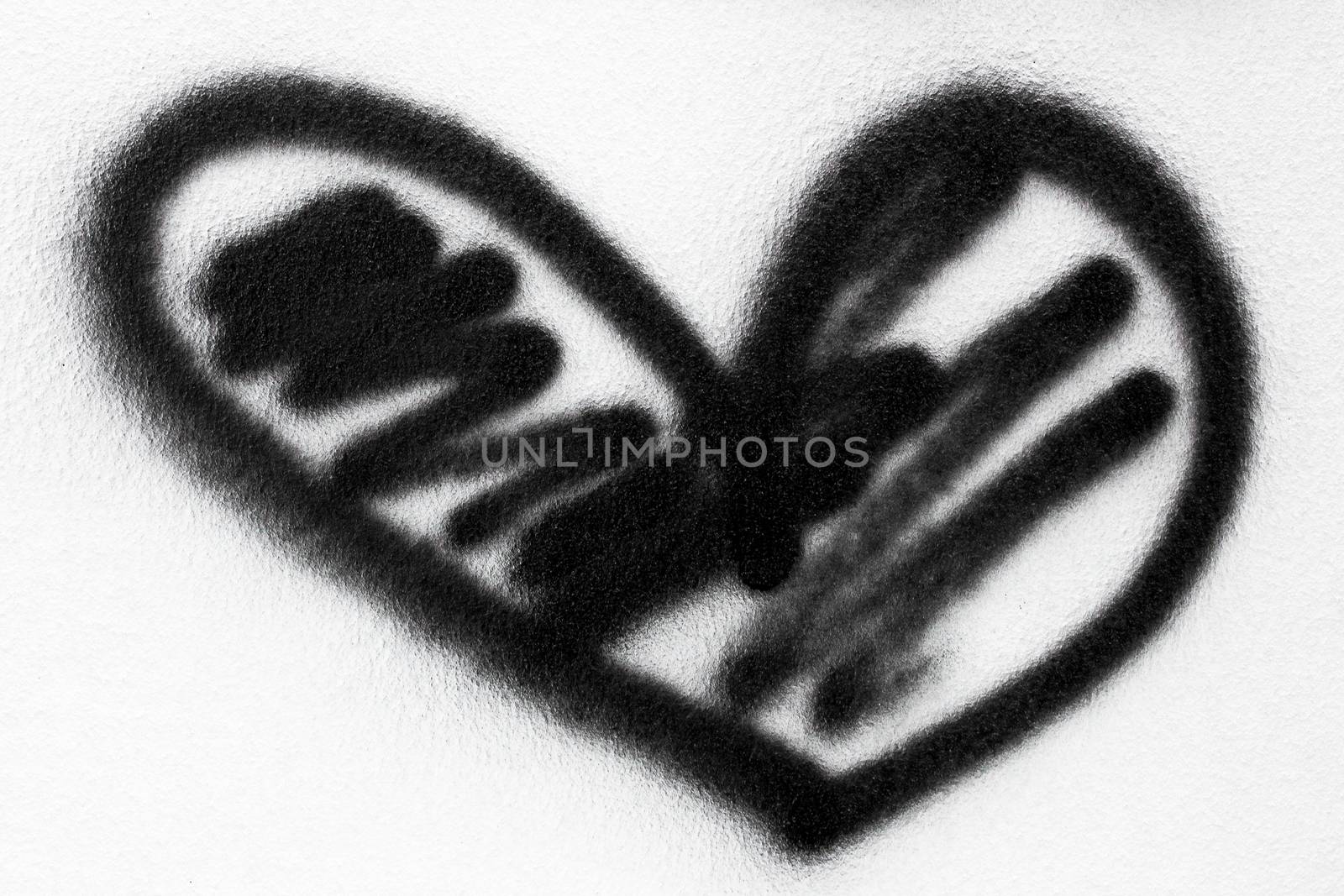 Black heart painted with spray paint on a white wall.