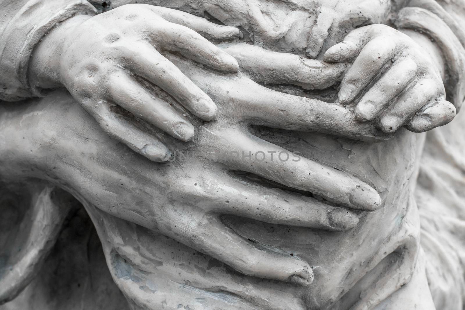 Detail of a marble statue with hands of child and woman together.