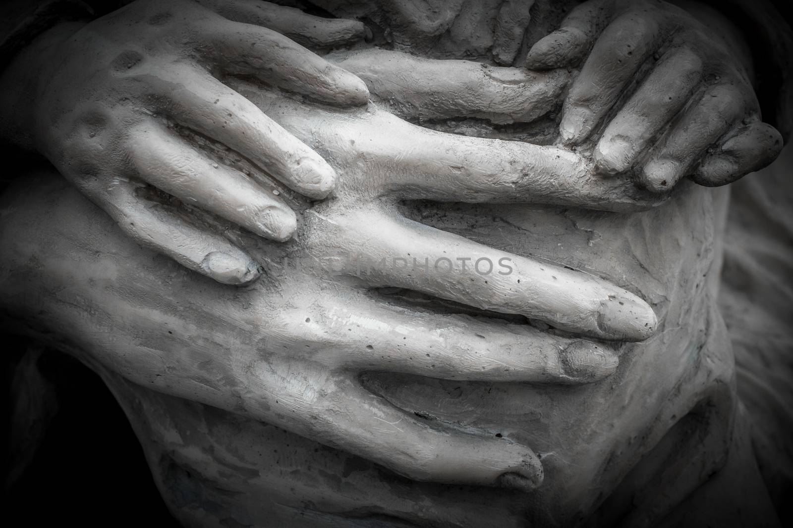 Detail of a marble statue with hands of child and woman together.
