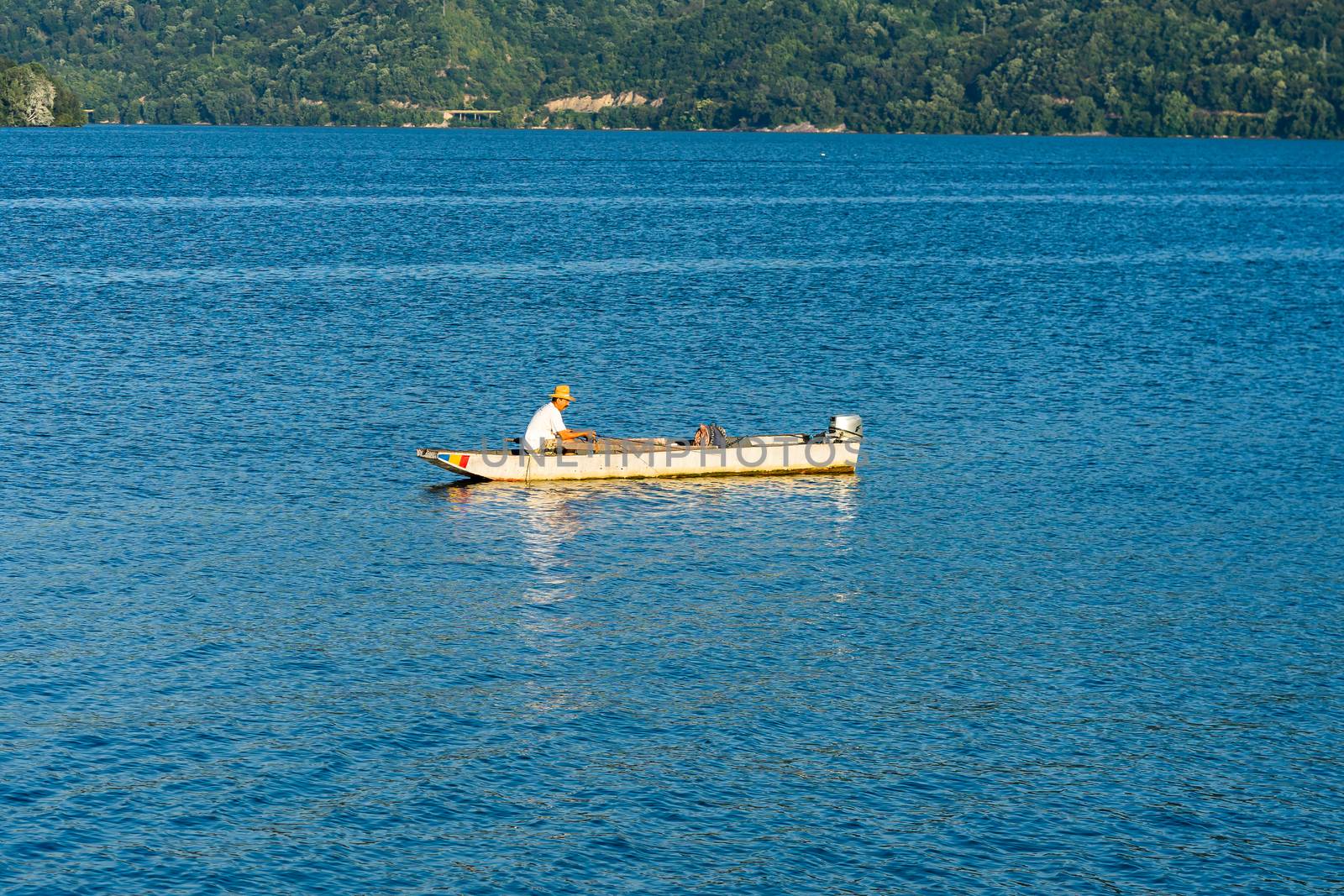 Man in boat relaxing and fishing on Danube river on a sunny day  by vladispas