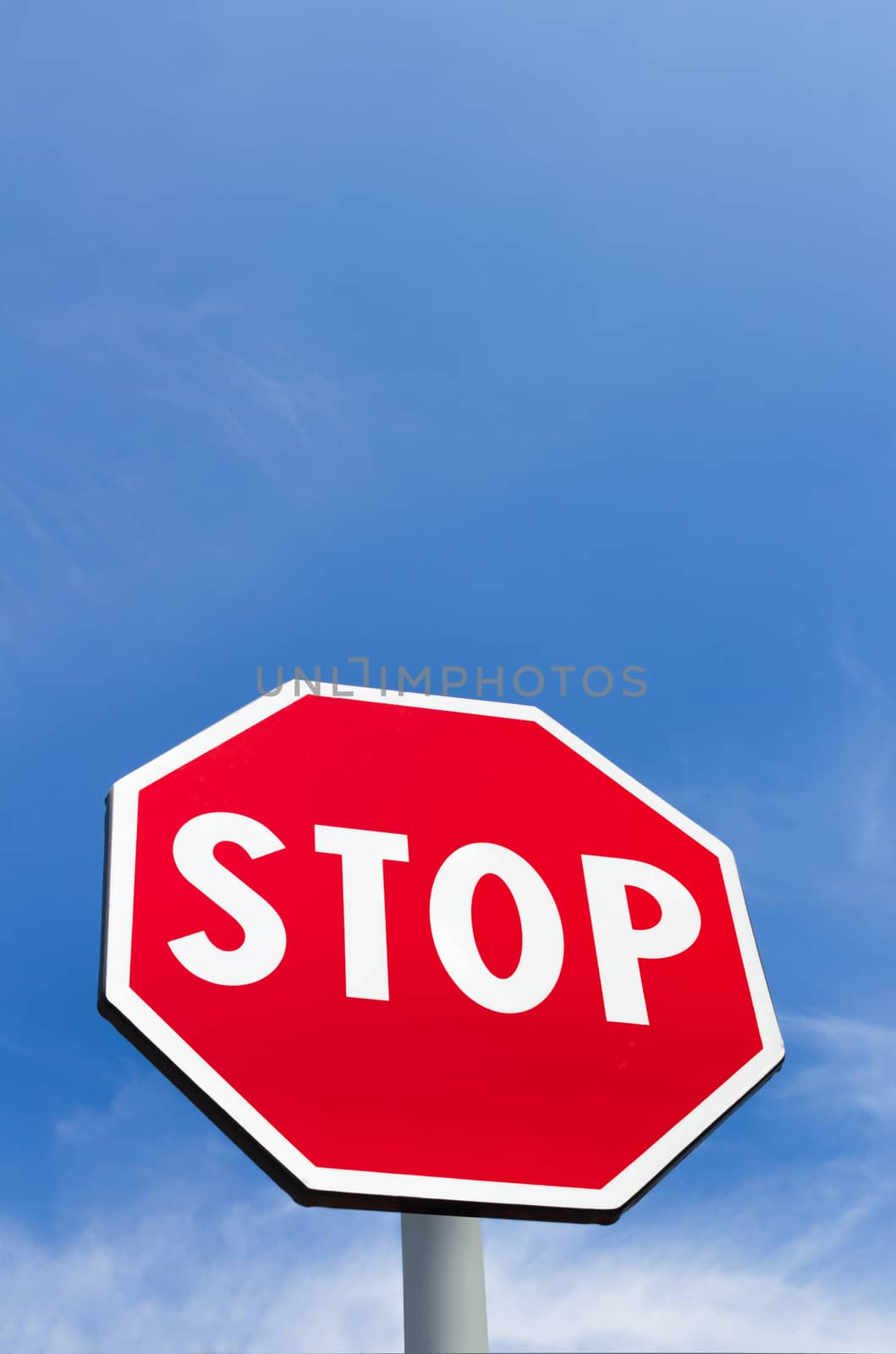 Stop sign isolated on a blue sky background with white clouds. Space for text.