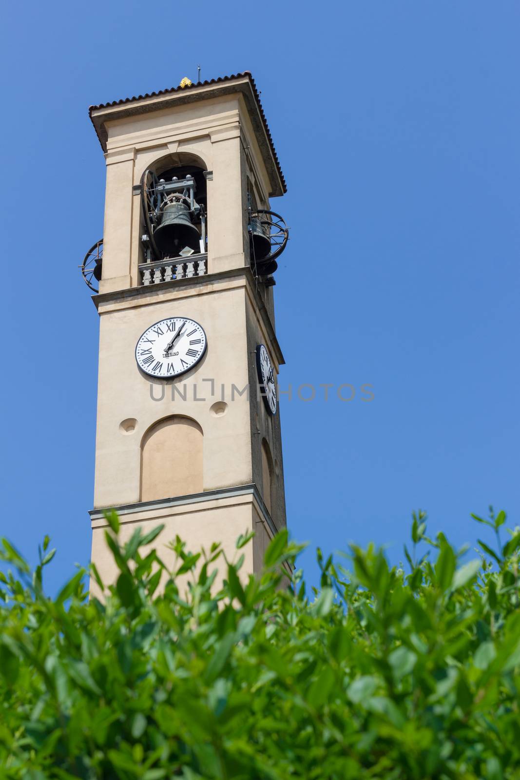 Clock and bell tower of a church in italy. Blue sky. Bottom view.
