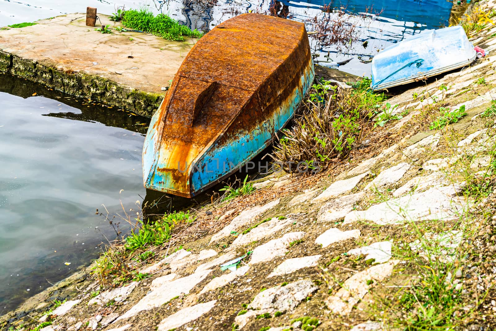 Old and rusty iron overturned boat on the shore, on the edge of  by vladispas