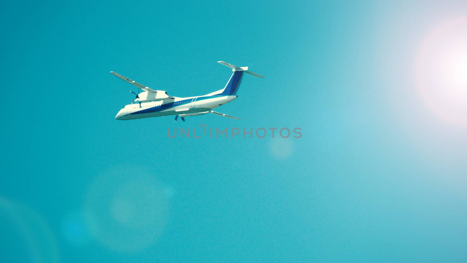 Airplane taking off to the blue sky from international airport runway in Sapporo Hokkaido Japan and have sun light flare to camera and shoot from uprisen or low angle view.