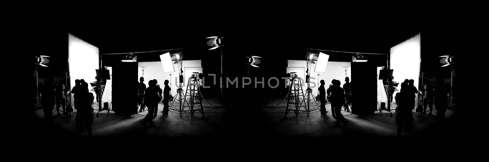 Silhouette images of video production behind the scenes or b-roll or making of TV commercial movie that film crew team lightman and cameraman working together with director in big studio with professional equipments 