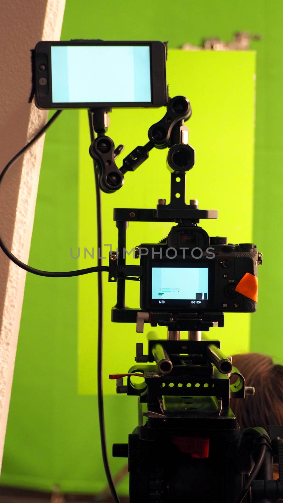 Behind the vdo camera in studio production that shooting or filming green screen background for chroma key technique in post process with professional crew teams and equipments.