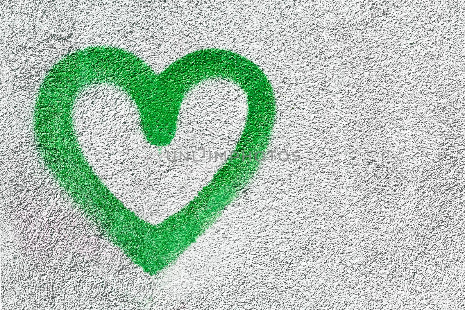 Green heart shaped on wall background. Symbol of love on rustic wall. It can be used as a Valentine's theme, poster, wallpaper, design t-shirts and more.
