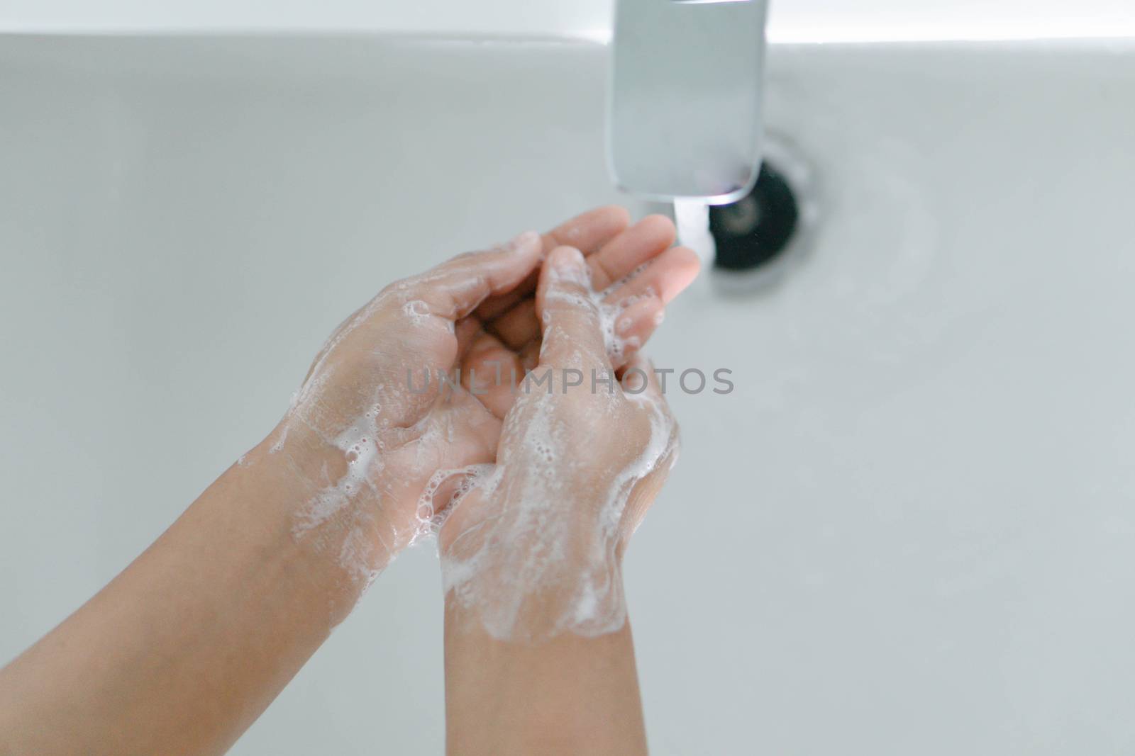 Closeup woman's hand washing with soap in bathroom, selective focus