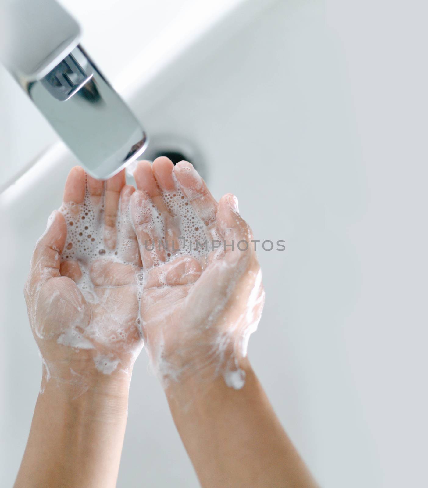 Closeup woman's hand washing with soap in bathroom, selective focus