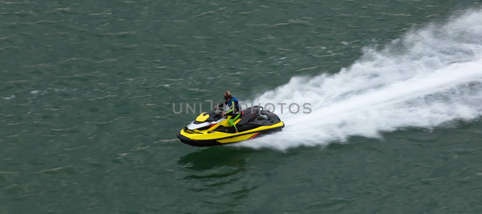 Yellow jetski moving very fast leaving white trace behind it. Close shot. Sports, competition concept. Aerial view.