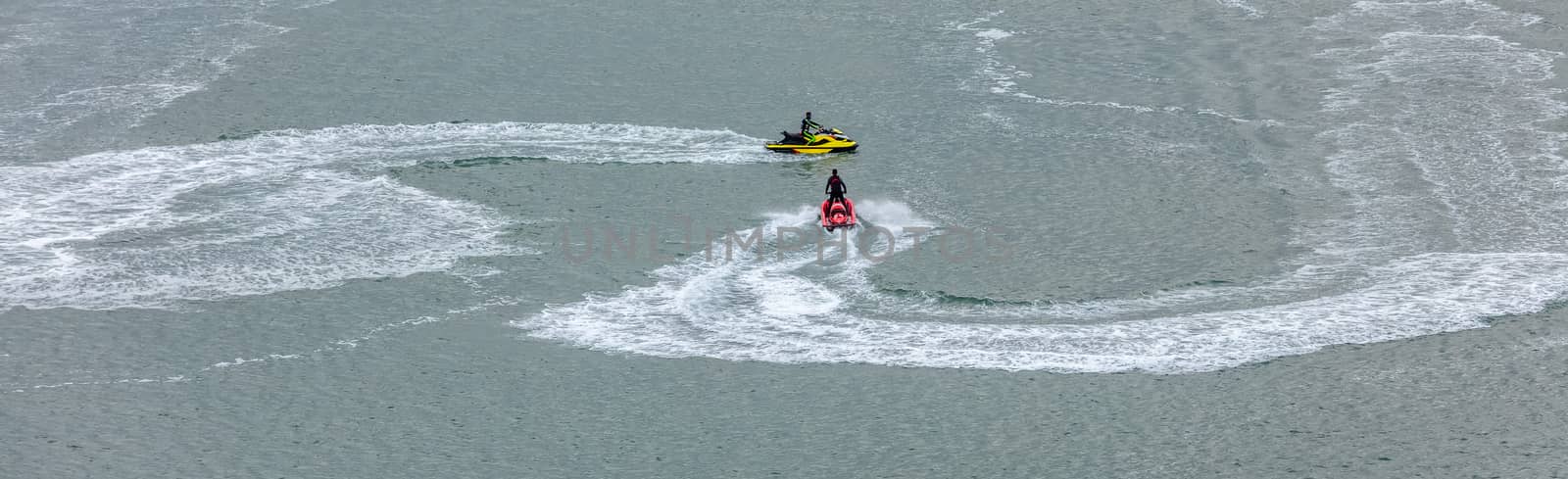 Red jetski moving towards a yellow jetski leaving white trace behind it. Sports, competition concept. Aerial view.