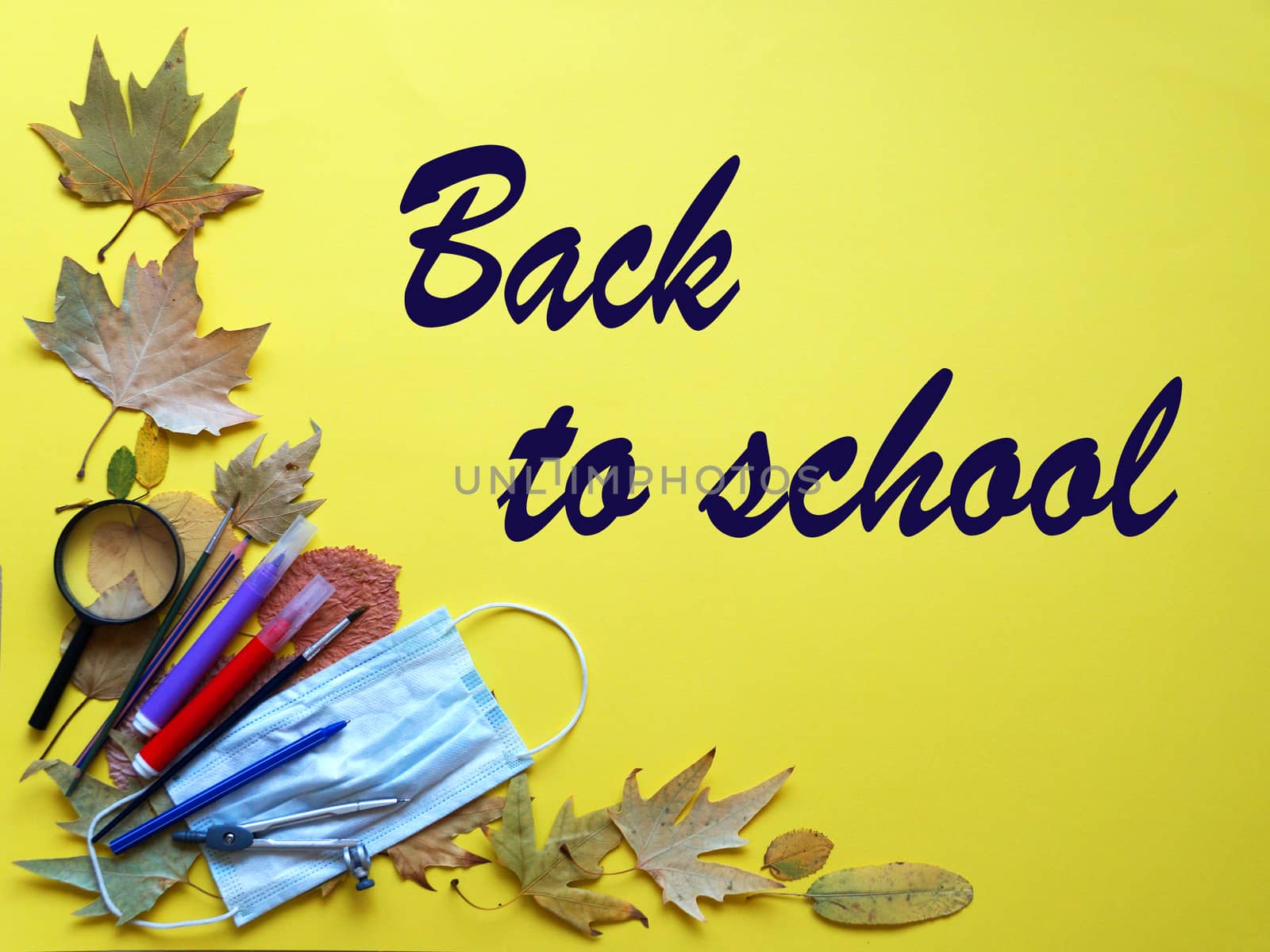 school supplies and autumn leaves on yellow background text back to school.