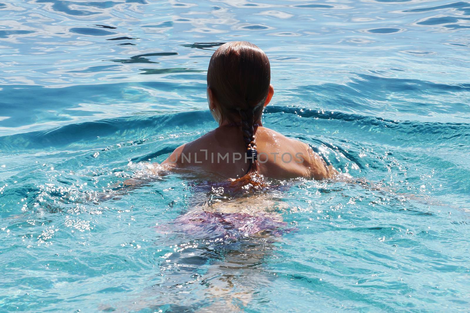 teenage girl swims in open water, close up rear view by Annado