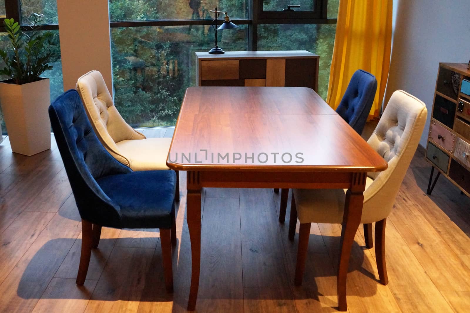 dining table and chairs in the living room by the large window.