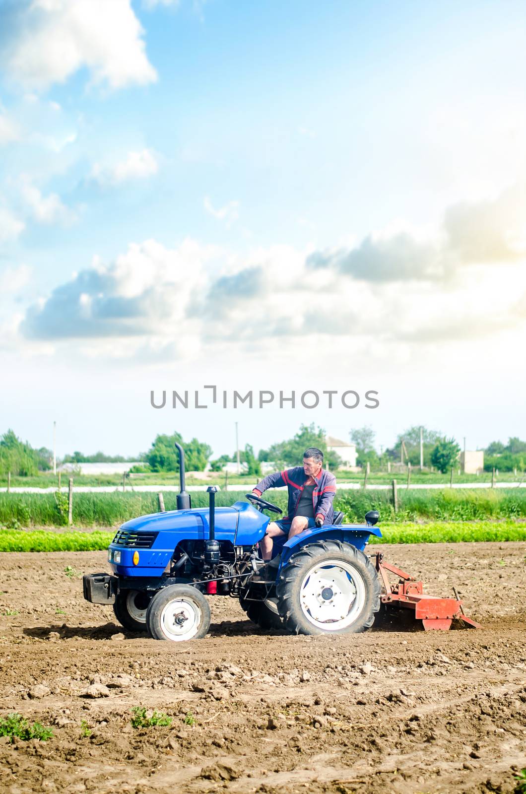 The farmer drives a tractor with a milling unit equipment. Loosening land cultivation Use of agricultural machinery to speed up work. Farming. Plowing field. The stage of preparing soil for planting. by iLixe48