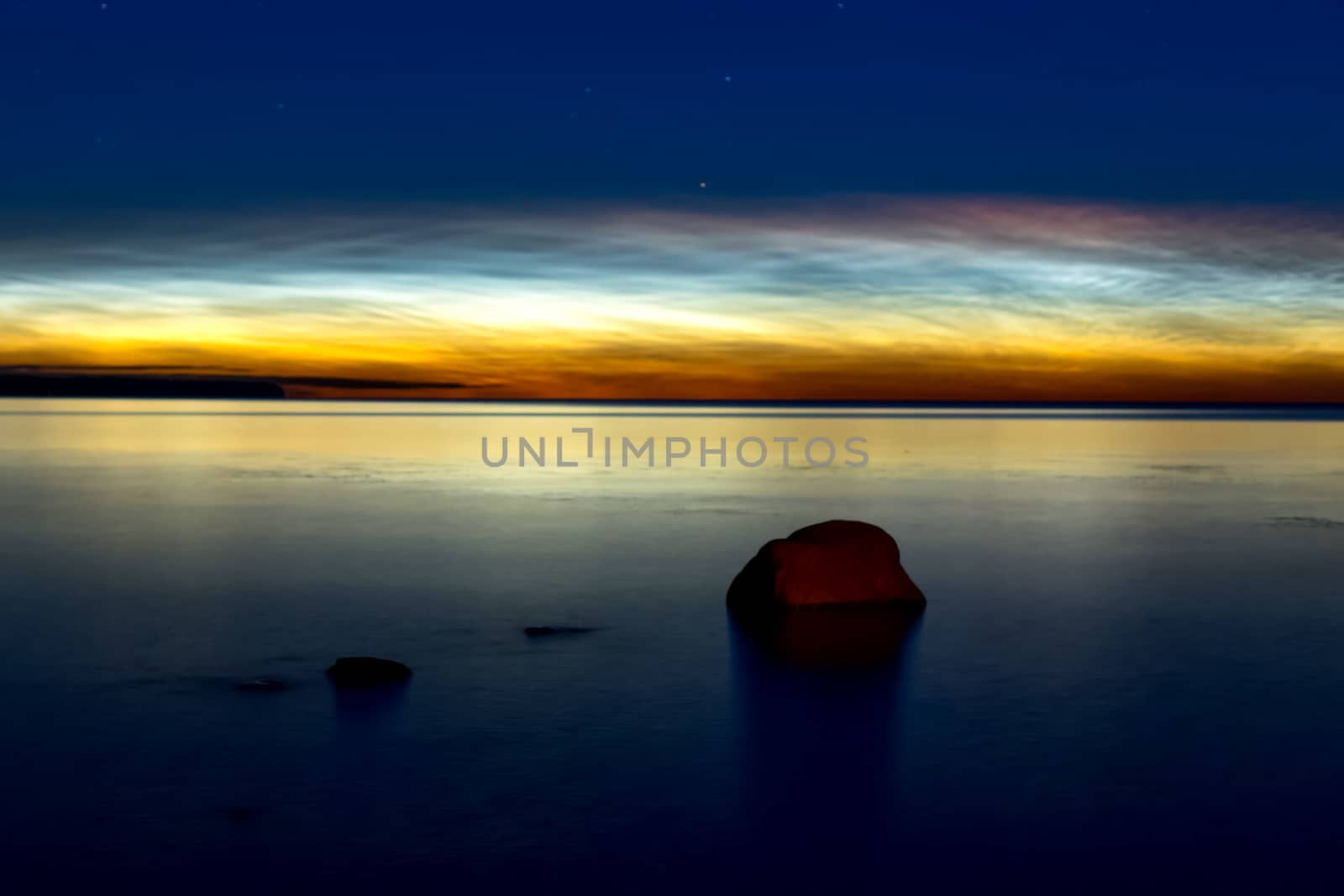 Dawn on the lake. Feathered clouds glow at dawn.
