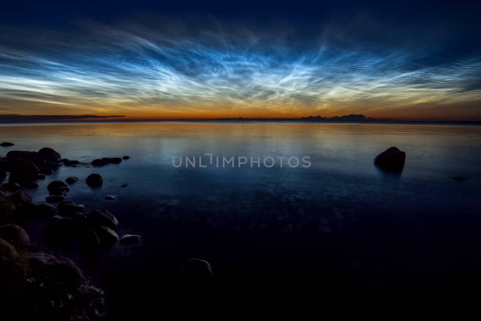 Dawn on the lake. Feathered clouds glow at dawn.