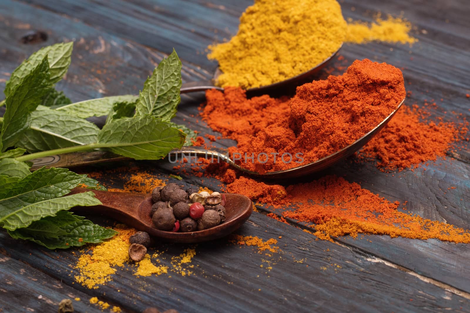 Colorful spices and wooden spoon on black background