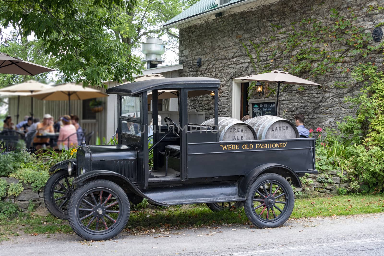 An ancient Truck with two barrels of beer as a brand name stands near the pub