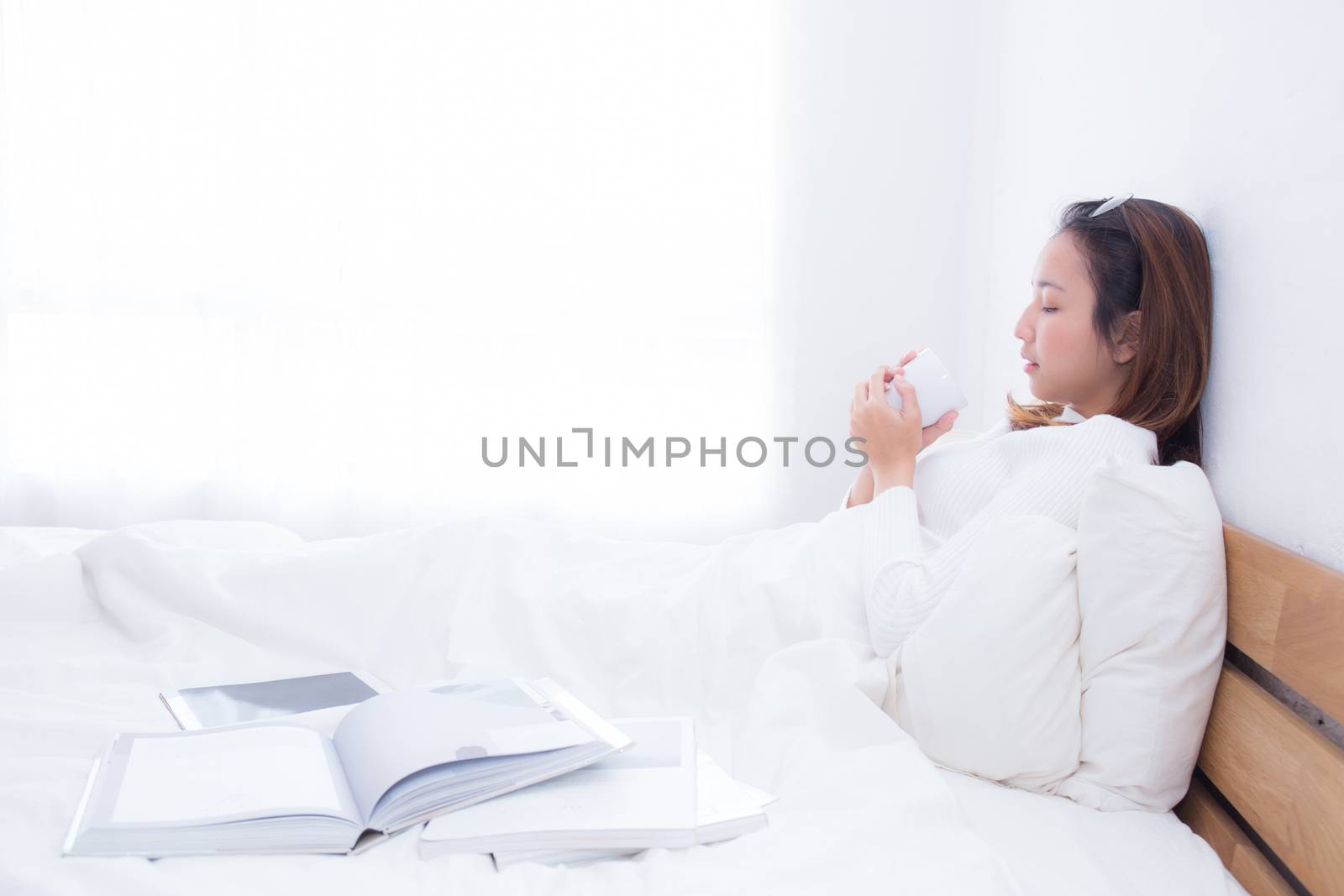 Asian woman with cup of coffee in bedroom with morning.