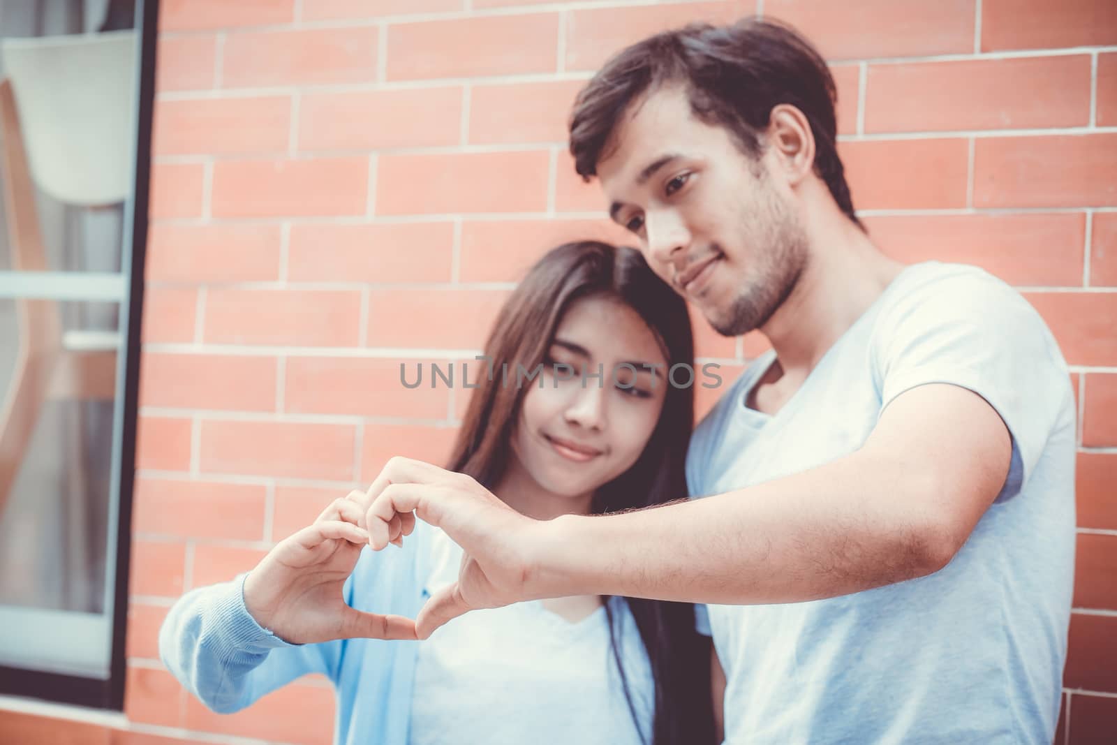 Closeup of young man and woman asian making heart shape with hand, Loving couple with heart shape of hand outdoors.