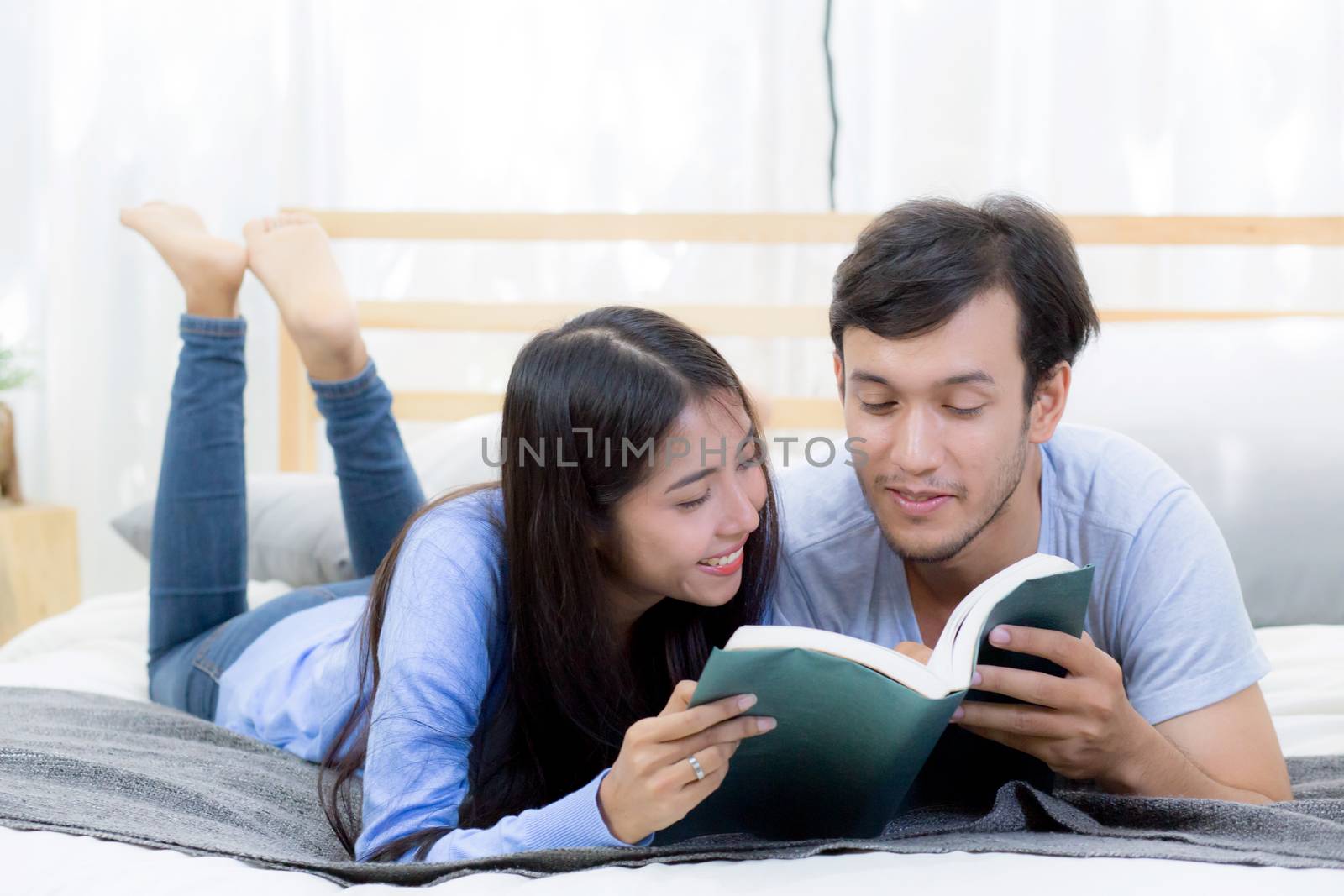 Couple reading a book together in bedroom on the morning with happiness.