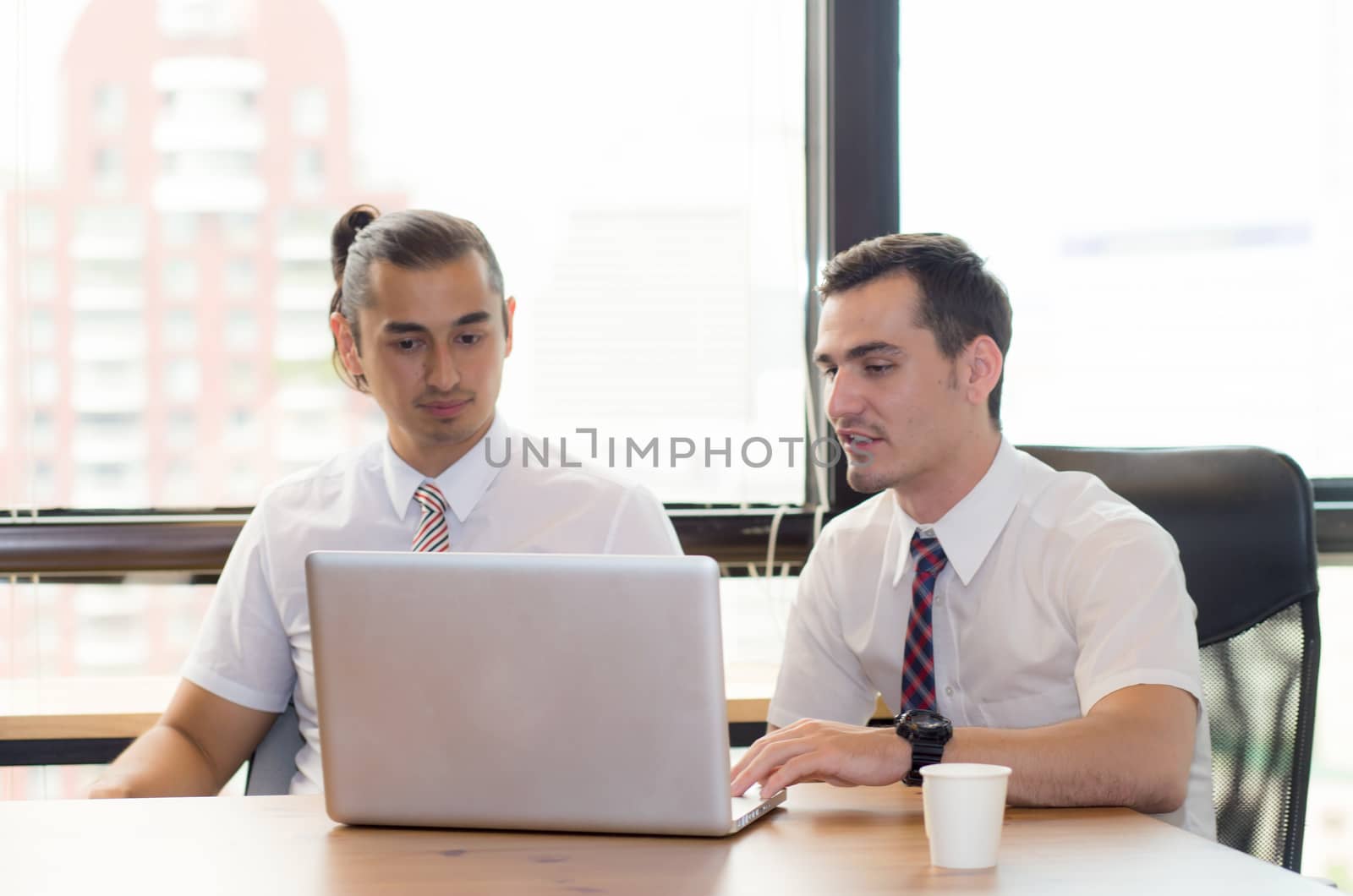 American people business two young caucasian modern man sitting in a meeting room using and looking laptop together.