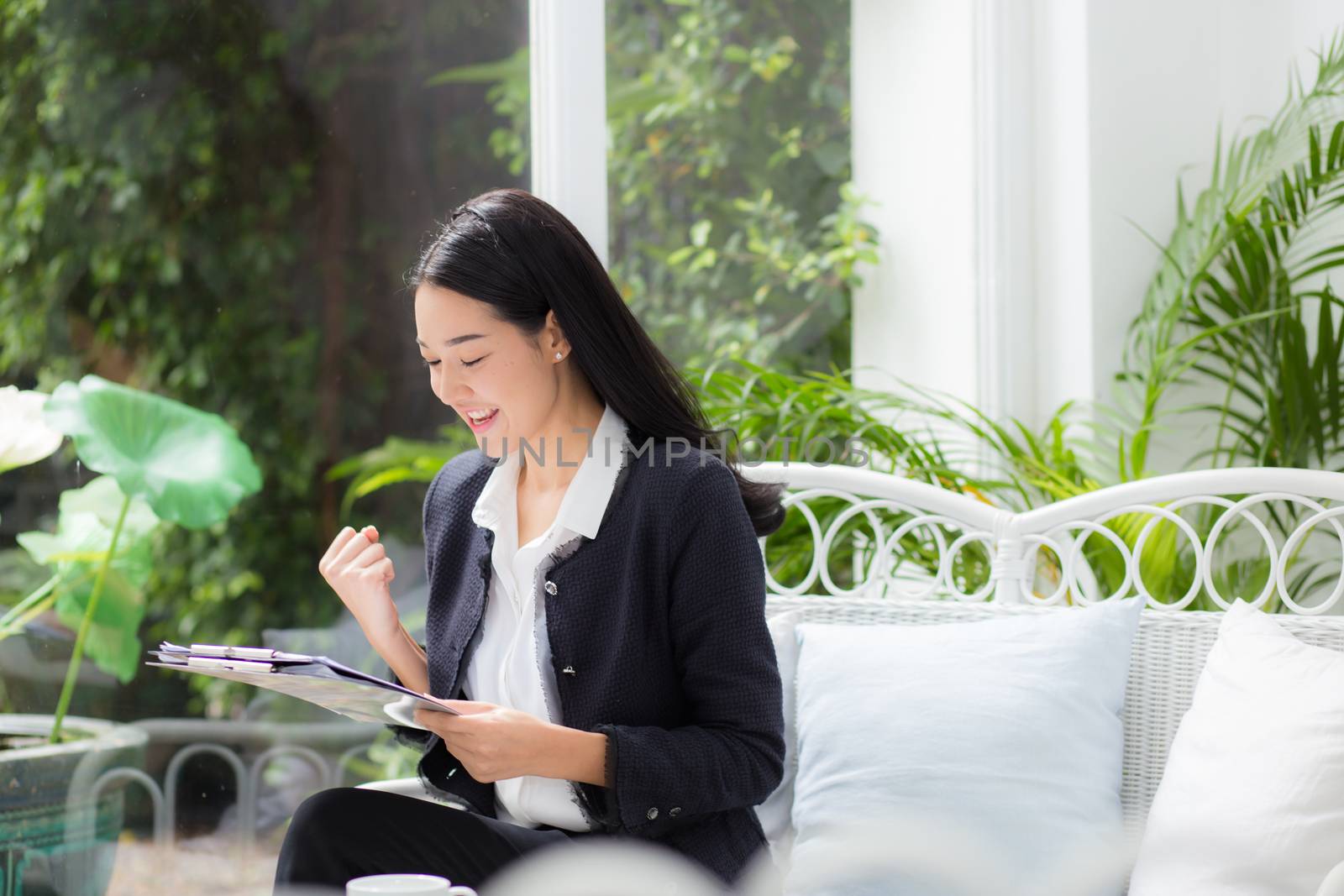 Asian business woman holding clipboard folder and gesture glad in the office.