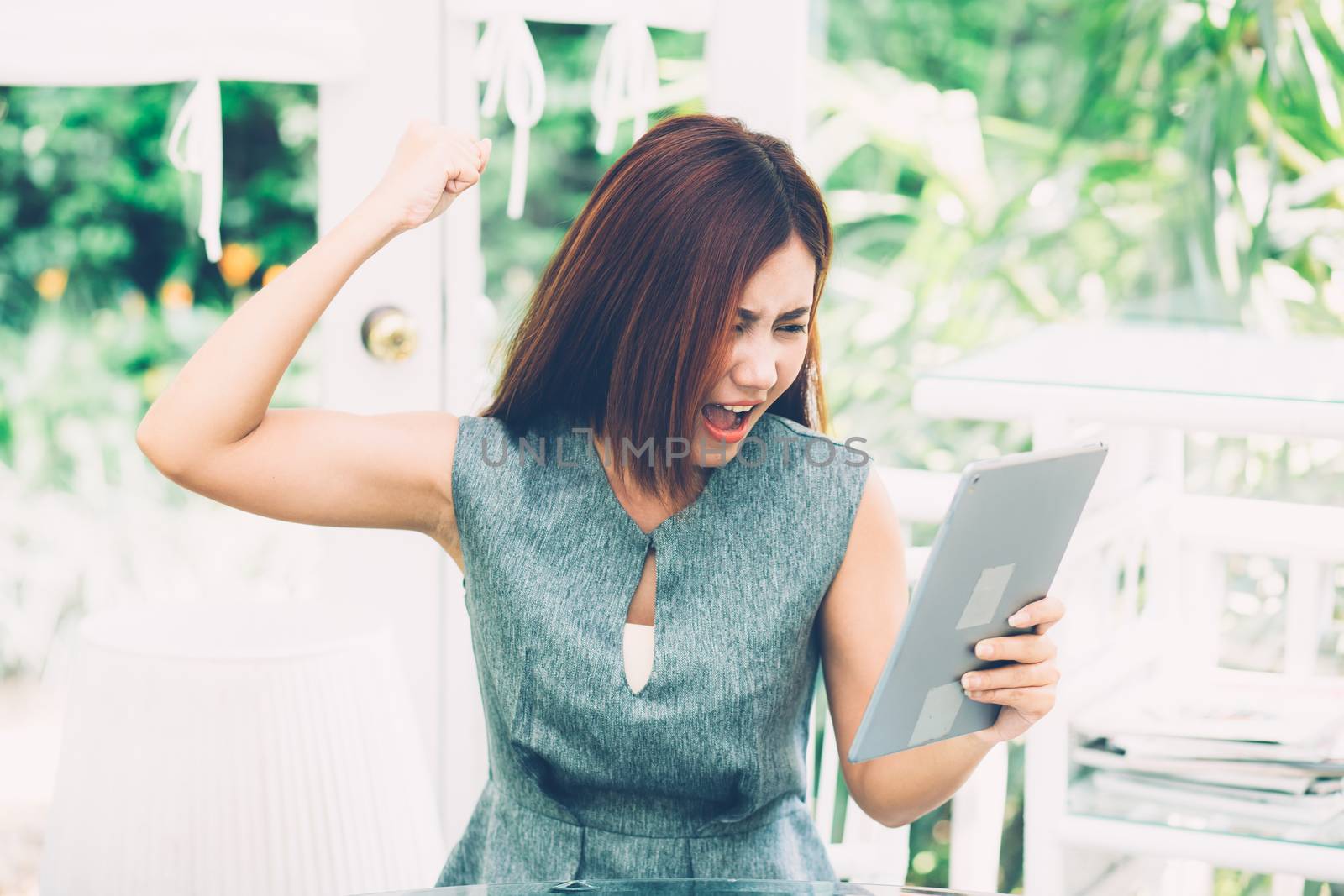 Asian woman looking tablet have a angry and upset outside in the by nnudoo