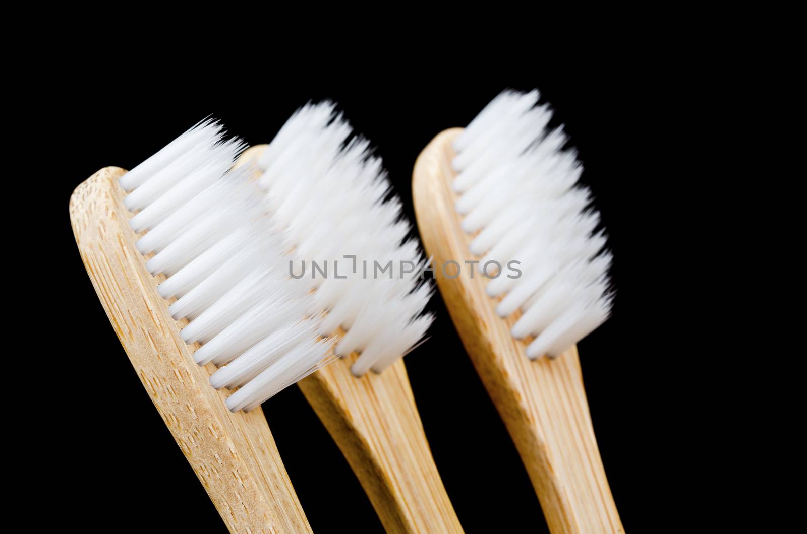 Bamboo toothbrush on black background. by Gamjai