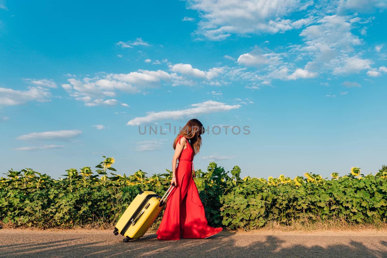 sad woman walking with a suitcase on the road.