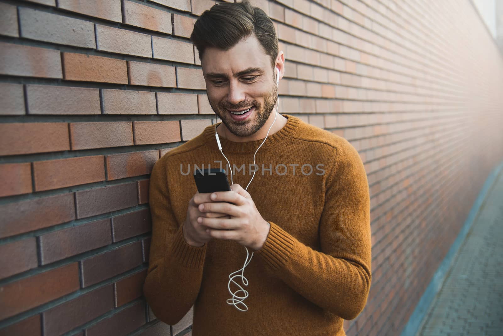 Portrait of stylish handsome young man with bristle standing outdoors.